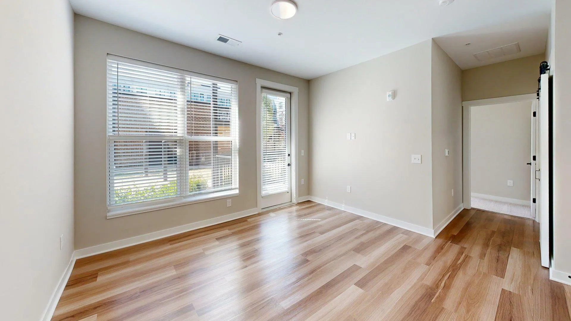 Bright room with large windows, modern wooden floors, and a fresh open feel.