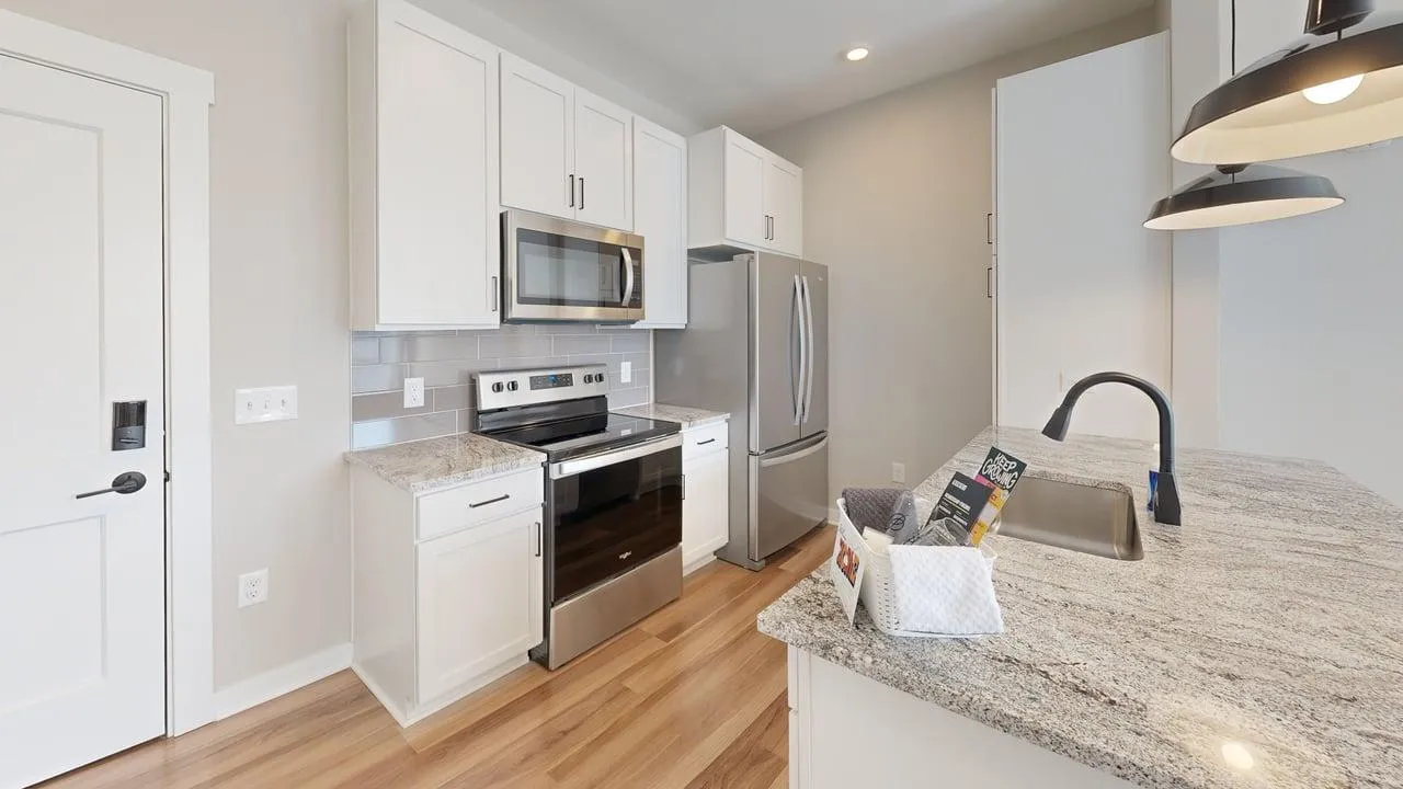 Modern kitchen with sleek stainless steel appliances, granite countertops, and elegant pendant lighting.