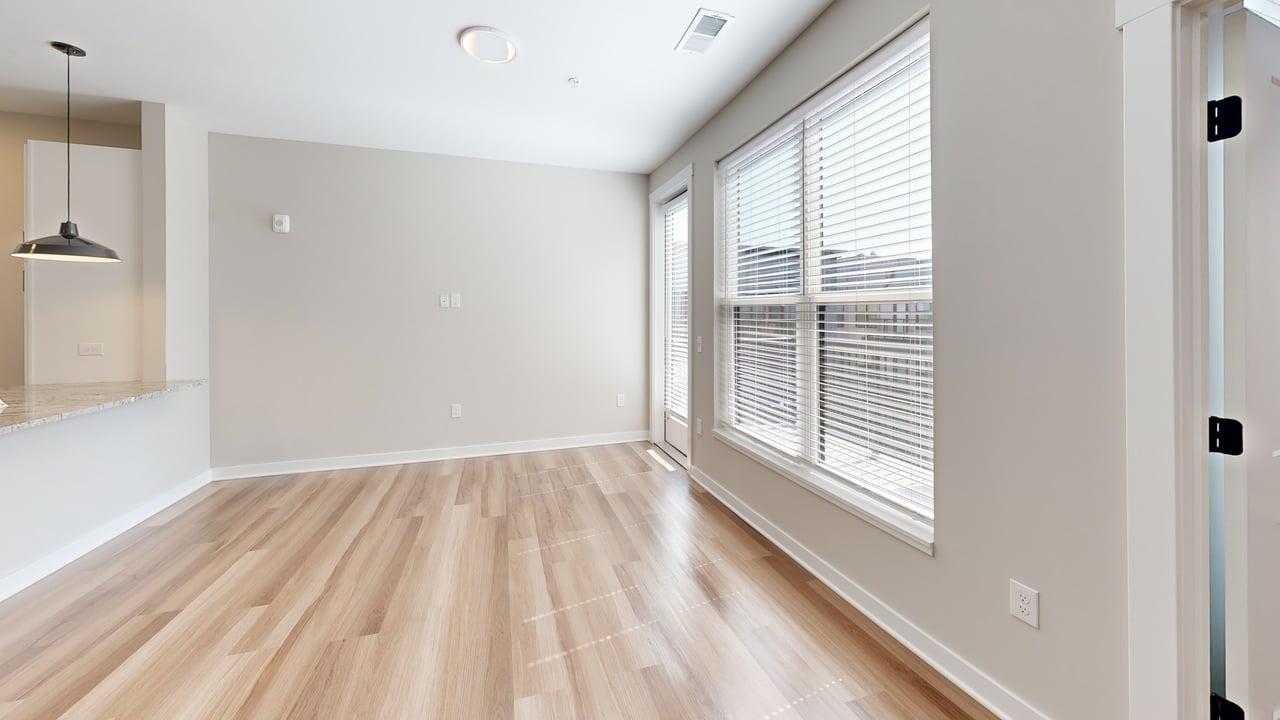 Bright apartment interior with large windows, modern pendant light, and elegant hardwood flooring.