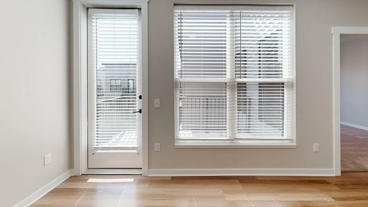 Bright room featuring large windows with blinds, natural light, and sleek wooden flooring.