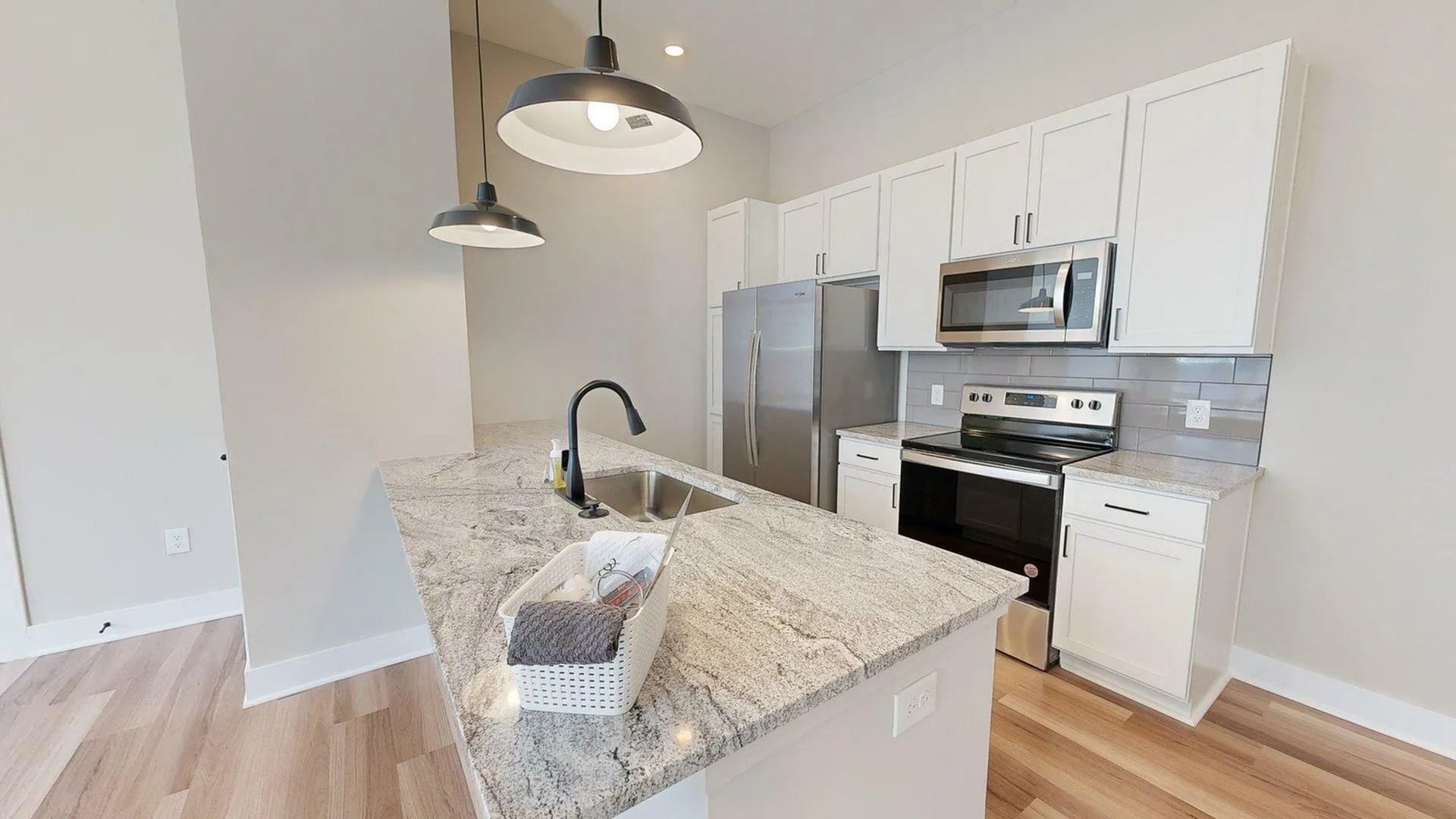 Sleek modern kitchen with granite countertops, stainless steel appliances, and stylish pendant lighting.