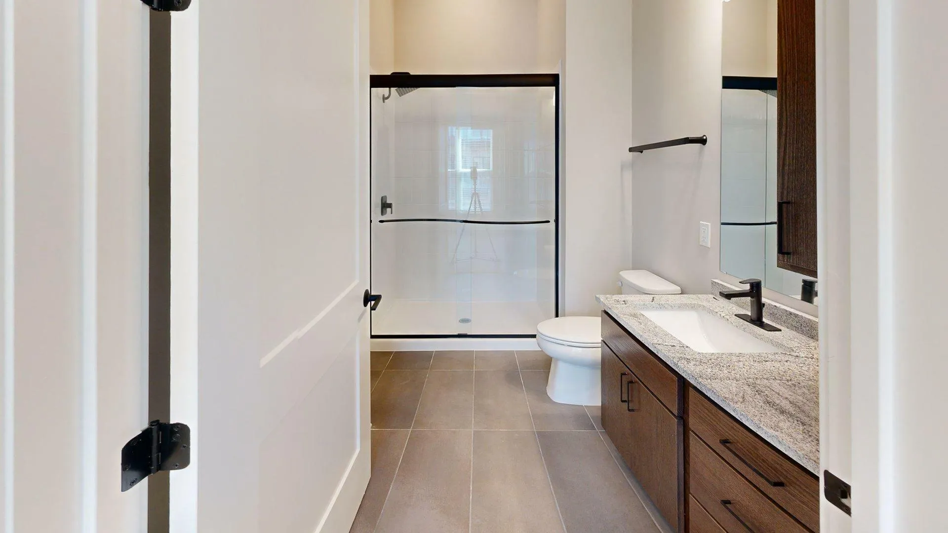 Modern bathroom with sleek glass shower, elegant granite countertop, and stylish dark wood cabinetry.