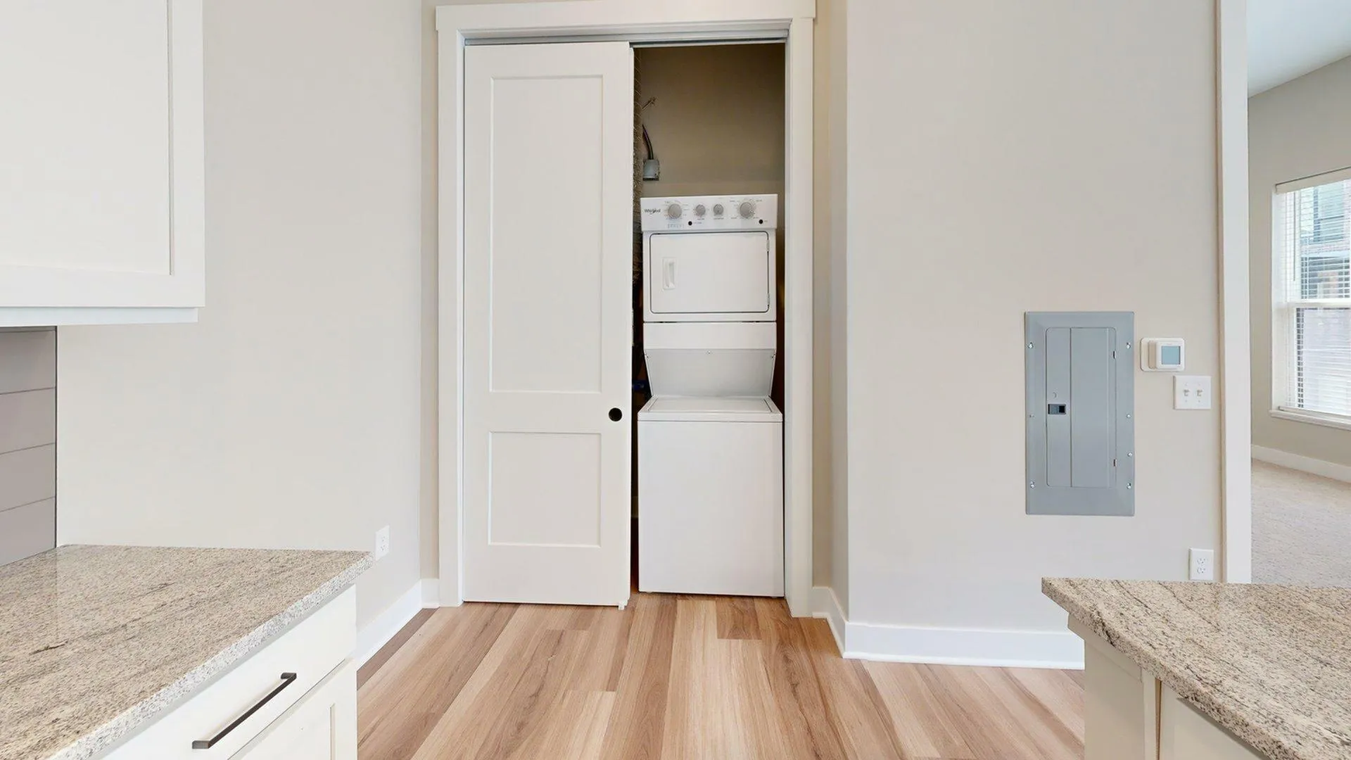 Modern apartment featuring a convenient in-unit stackable washer and dryer, nestled within a bright, open-concept kitchen area with elegant granite countertops and sleek cabinetry.