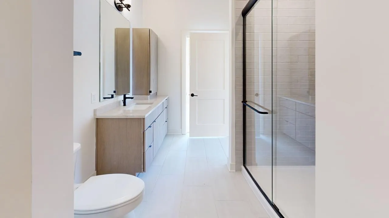 Elegant modern bathroom featuring sleek glass shower, dual vanity sinks, and stylish cabinetry.