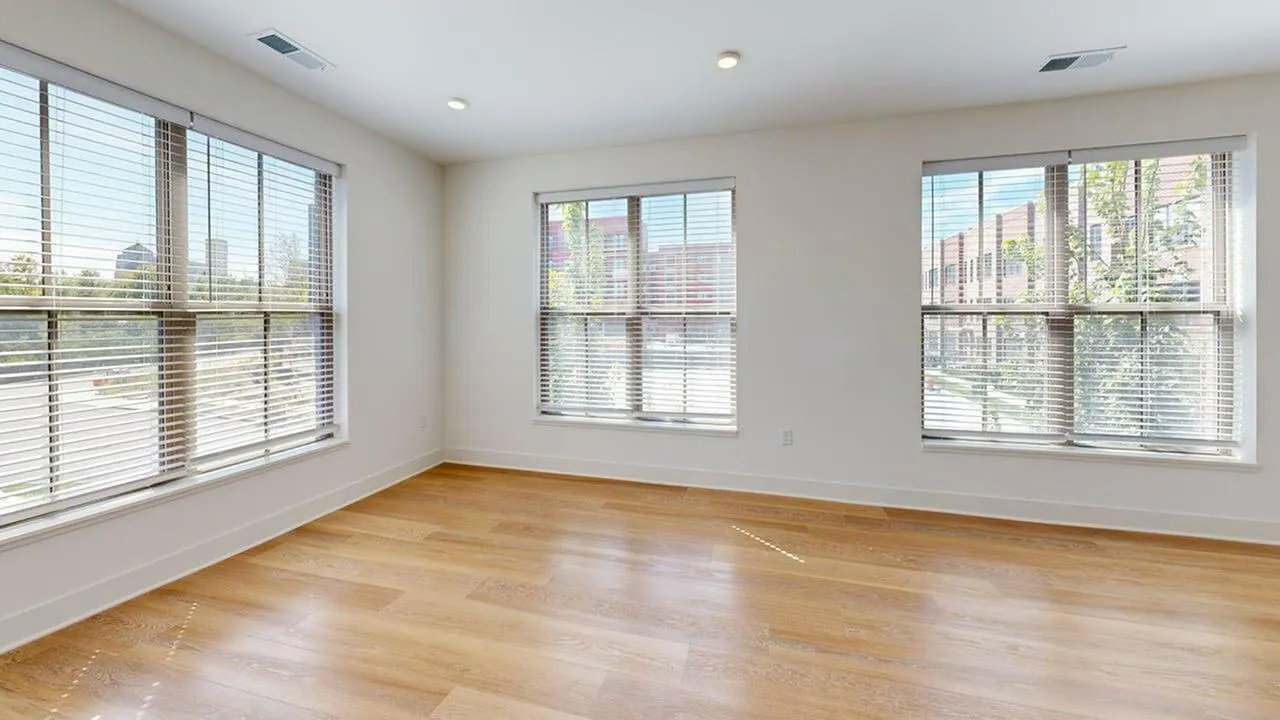 Bright, sunlit room with large windows and elegant wooden flooring, perfect for creating a cozy living space.