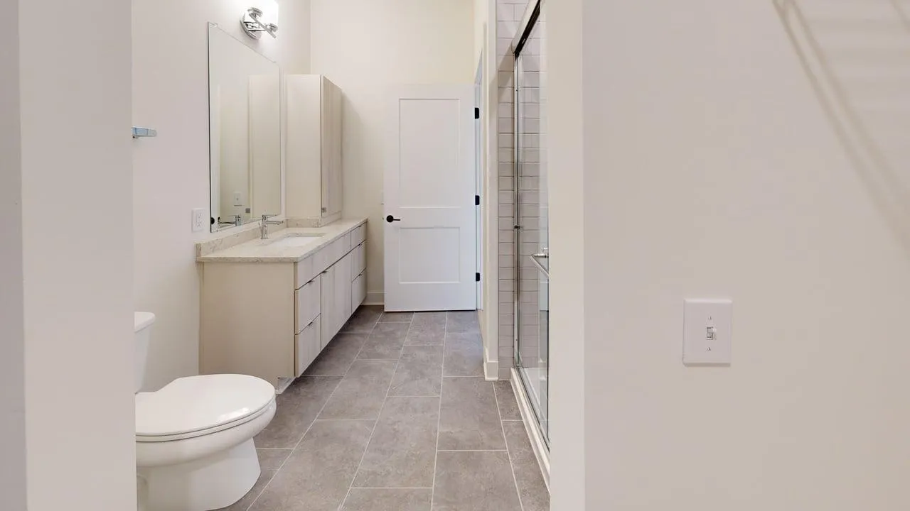 Modern bathroom with elegant tile flooring, spacious vanity with double sinks, and a sleek shower design.