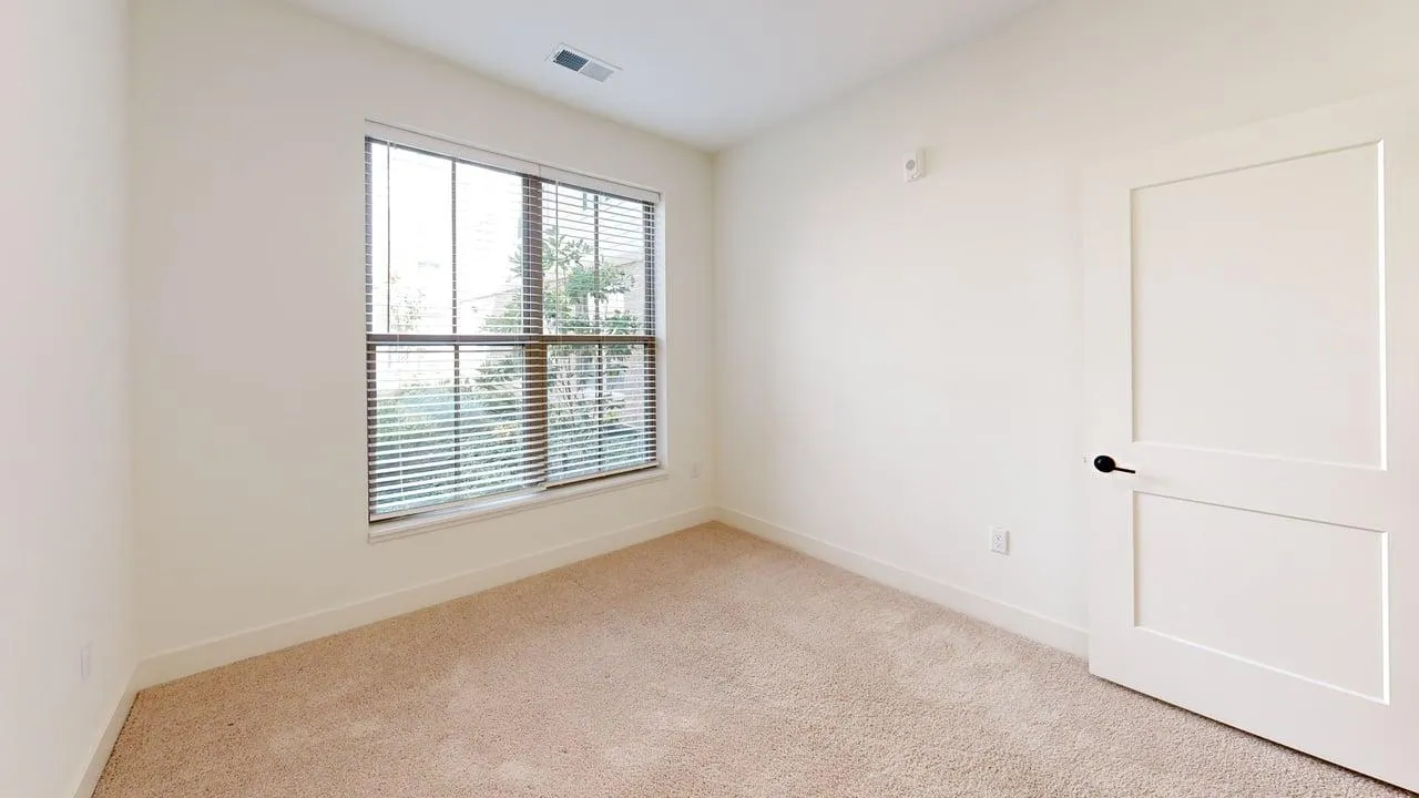 Bright and airy bedroom with large window, soft carpet, and modern door design.