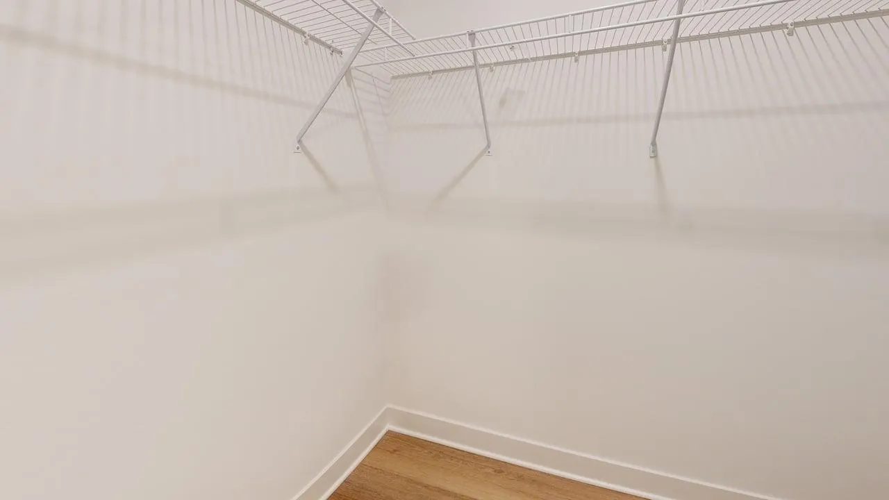 Spacious walk-in closet with hardwood flooring and ample shelving for organized storage.