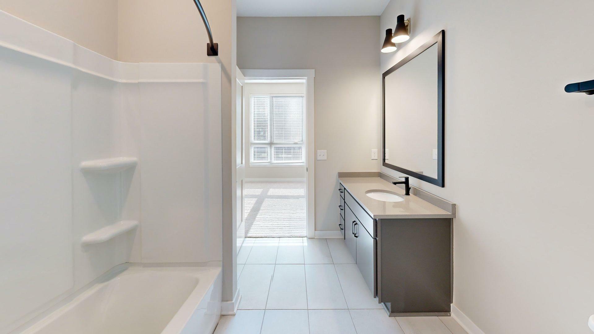 Modern bathroom with elegant vanity, large mirror, and spacious shower area, filled with natural light.