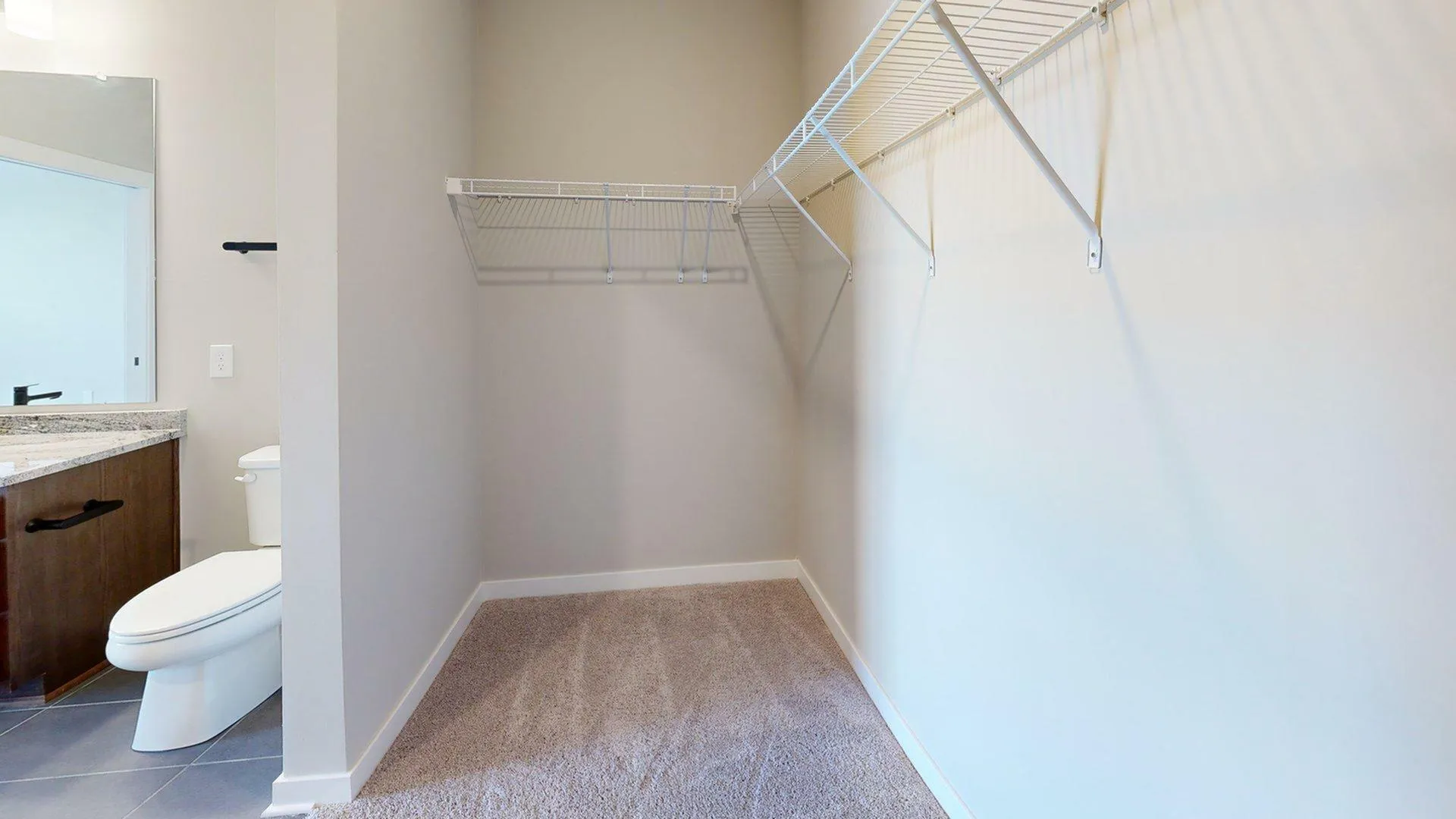 Spacious walk-in closet with hanging shelves, connected to a chic bathroom with modern fixtures.