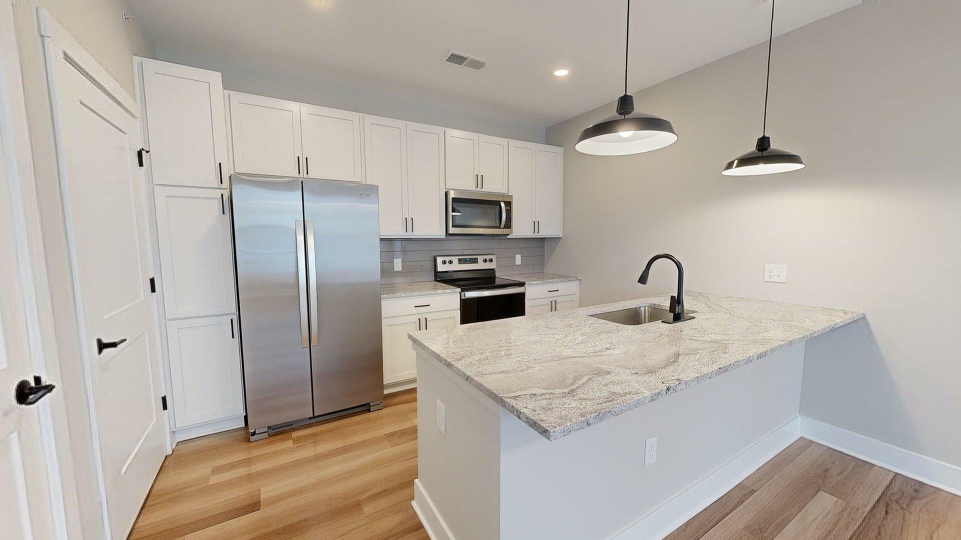 Modern kitchen with sleek white cabinetry, stainless steel appliances, and elegant lighting fixtures.