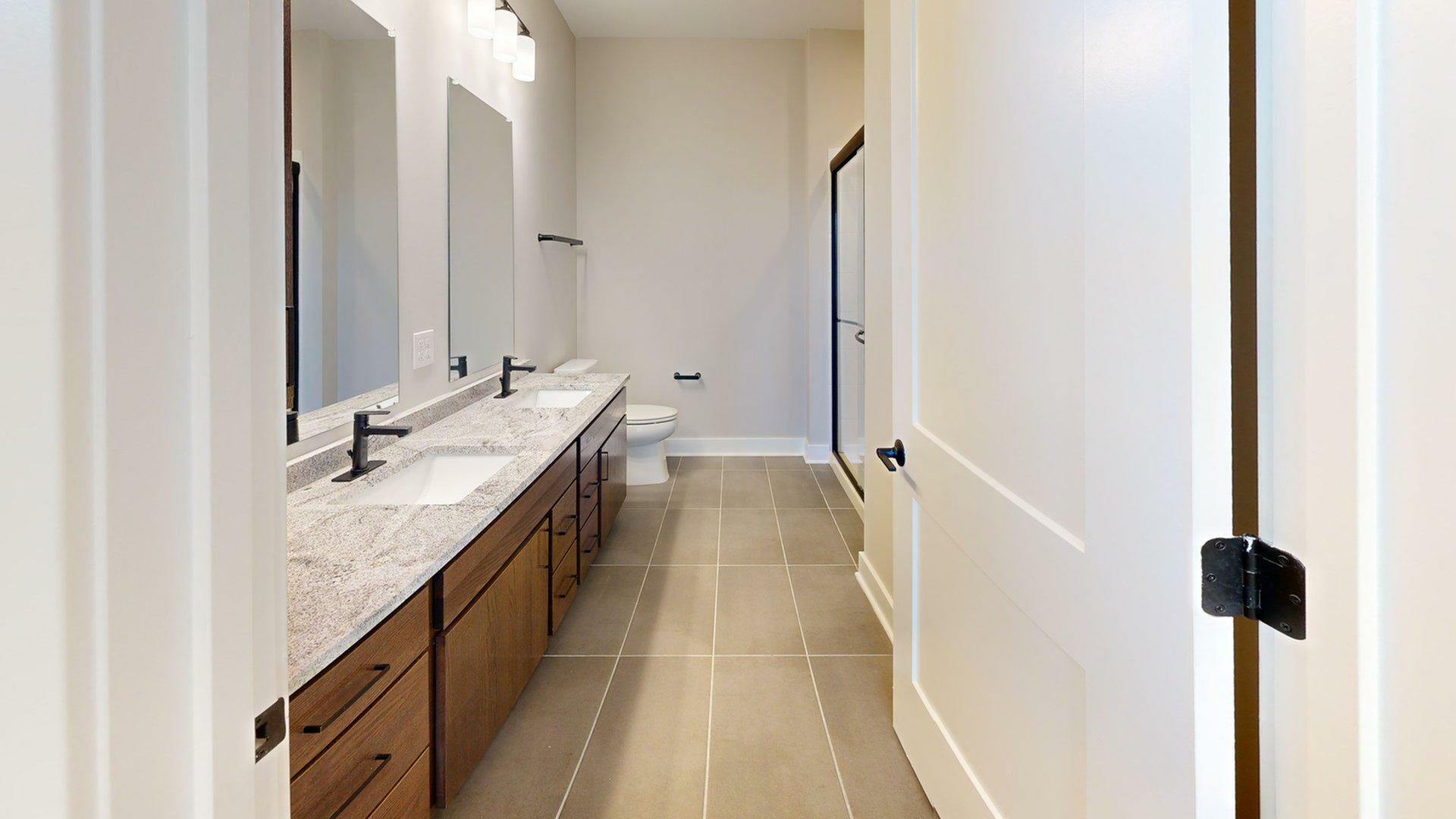 Elegant bathroom featuring a dual-sink vanity with sleek black fixtures and a spacious walk-in shower.