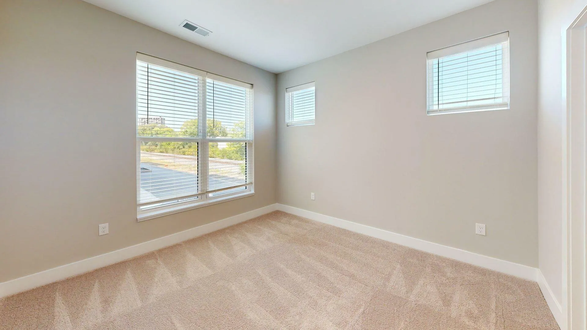 Bright and airy bedroom featuring large windows with scenic views and plush carpet flooring, perfect for a cozy retreat.