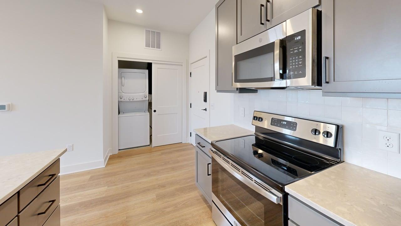 Modern kitchen with sleek stainless steel appliances, elegant cabinetry, and in-unit stacked washer and dryer.