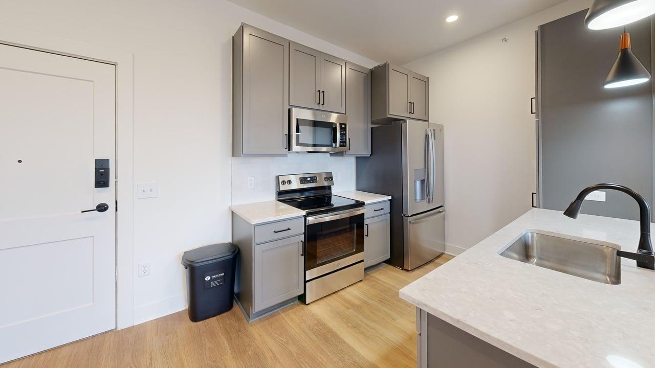 Modern kitchen with sleek stainless steel appliances, elegant gray cabinetry, and a spacious countertop adjacent to a handy sink.