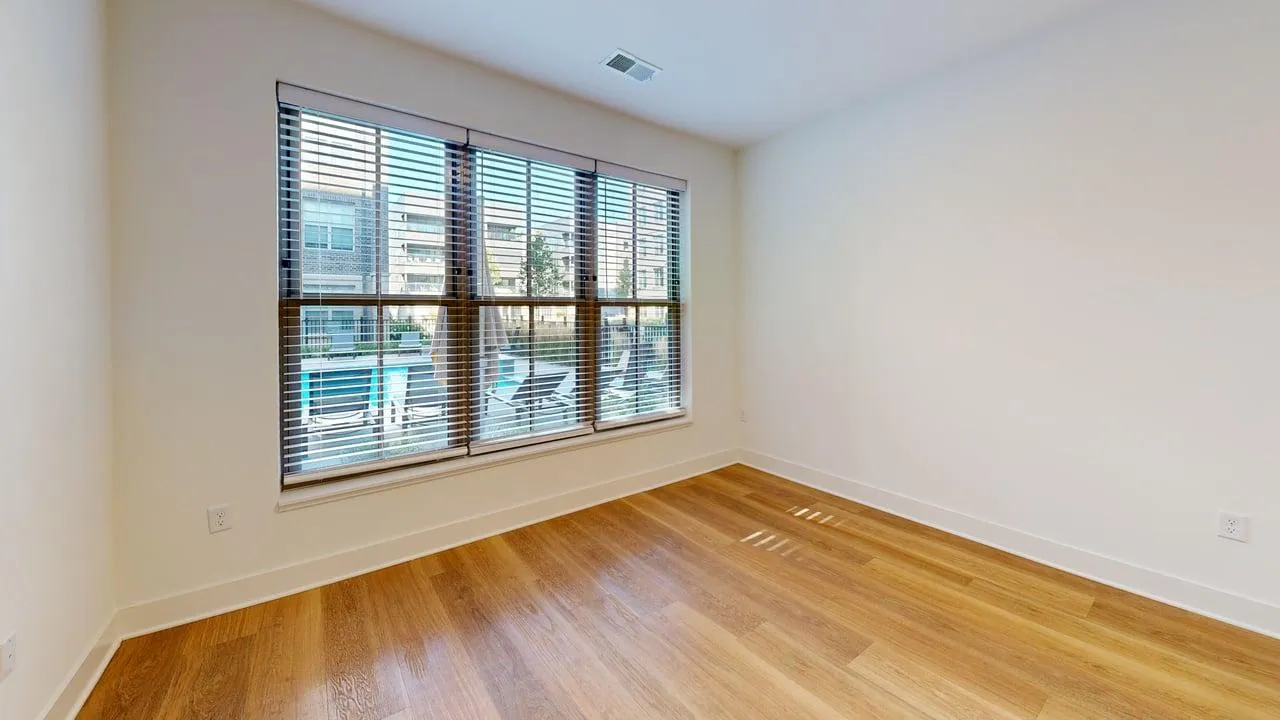 Bright room with large windows offering a serene pool view, featuring elegant hardwood flooring and ample natural light.