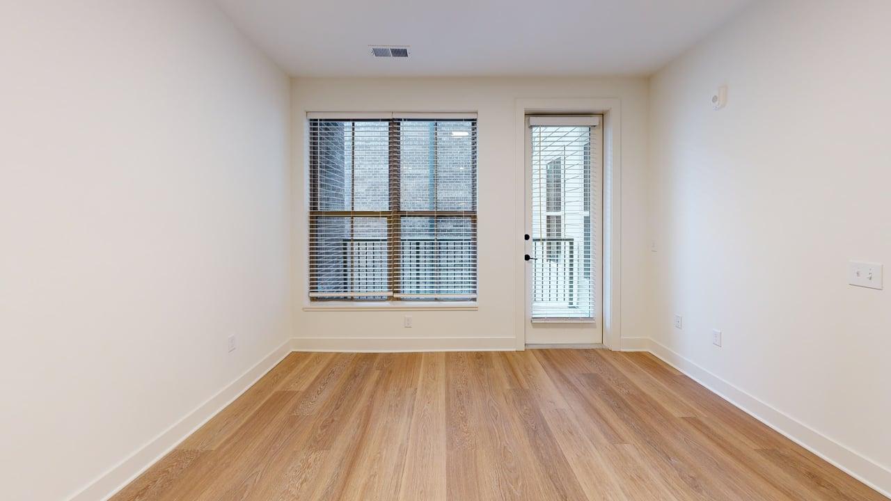 Bright, airy room with large window and wooden flooring, ideal for a cozy home office or serene reading nook.