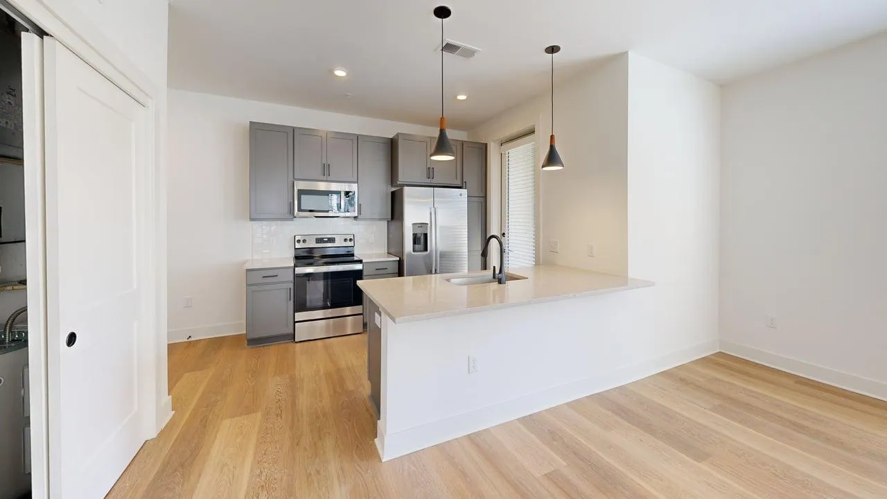 Bright modern kitchen with sleek gray cabinets, stainless steel appliances, and elegant pendant lighting.