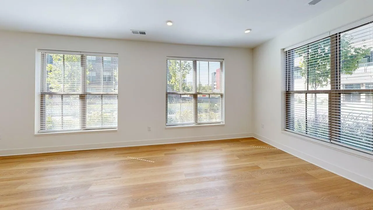 Bright and spacious room with large windows and elegant hardwood flooring, perfect for natural light.