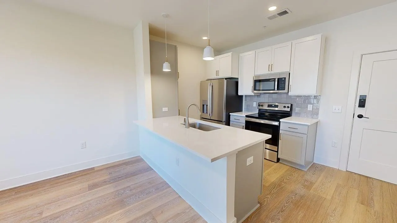 Contemporary kitchen with sleek white cabinets, modern appliances, and a spacious island with pendant lighting.