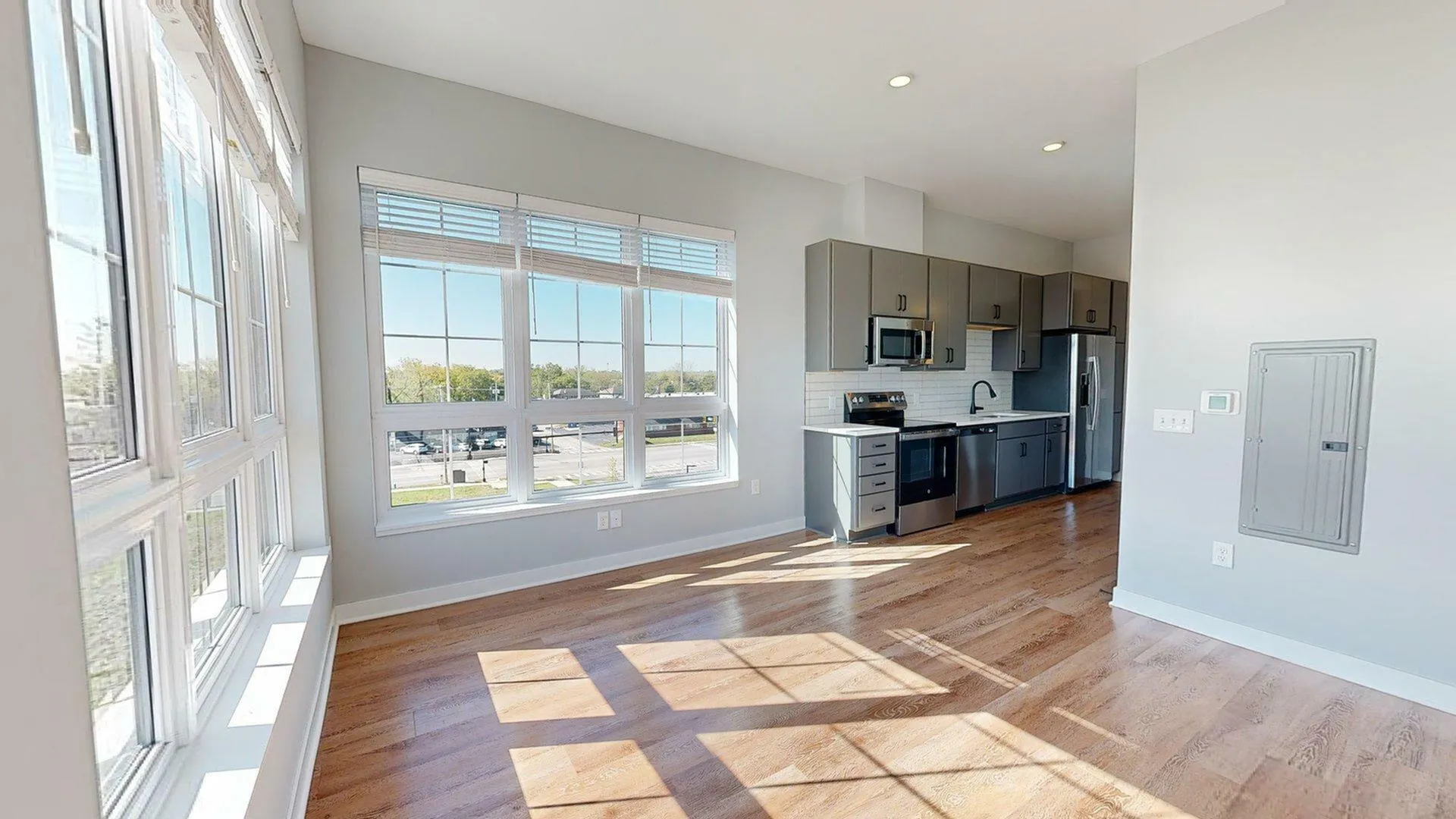 Bright, modern kitchen with stainless steel appliances and large windows offering ample natural light and a city view.