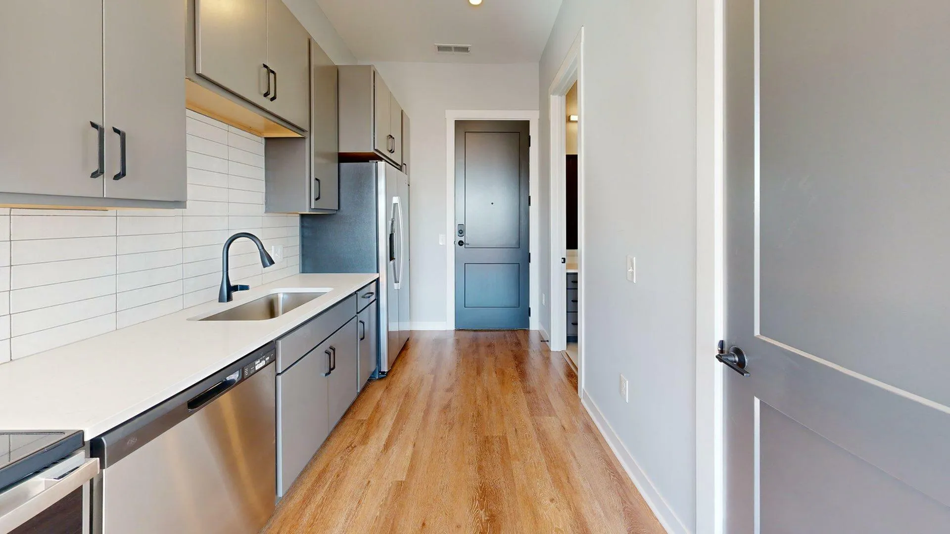 Modern kitchen with sleek gray cabinetry, stainless steel appliances, and elegant hardwood flooring.