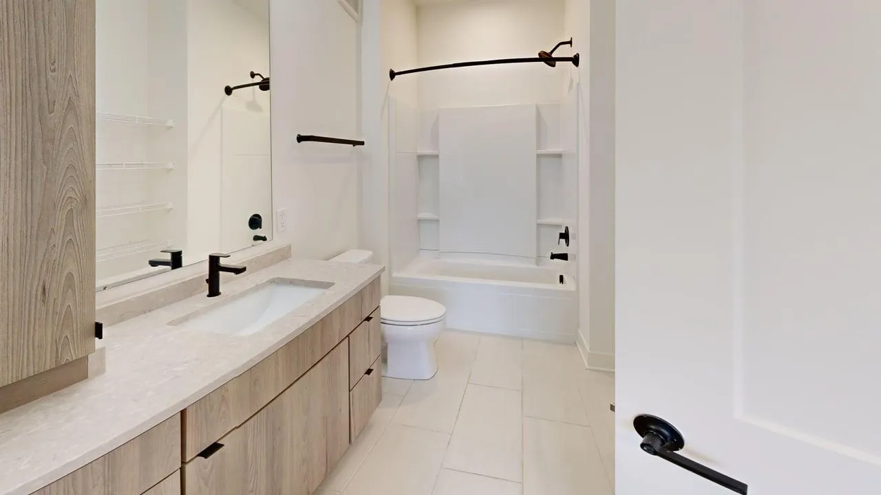 Modern bathroom featuring a light wood vanity, sleek fixtures, and a pristine bathtub with built-in shelving.