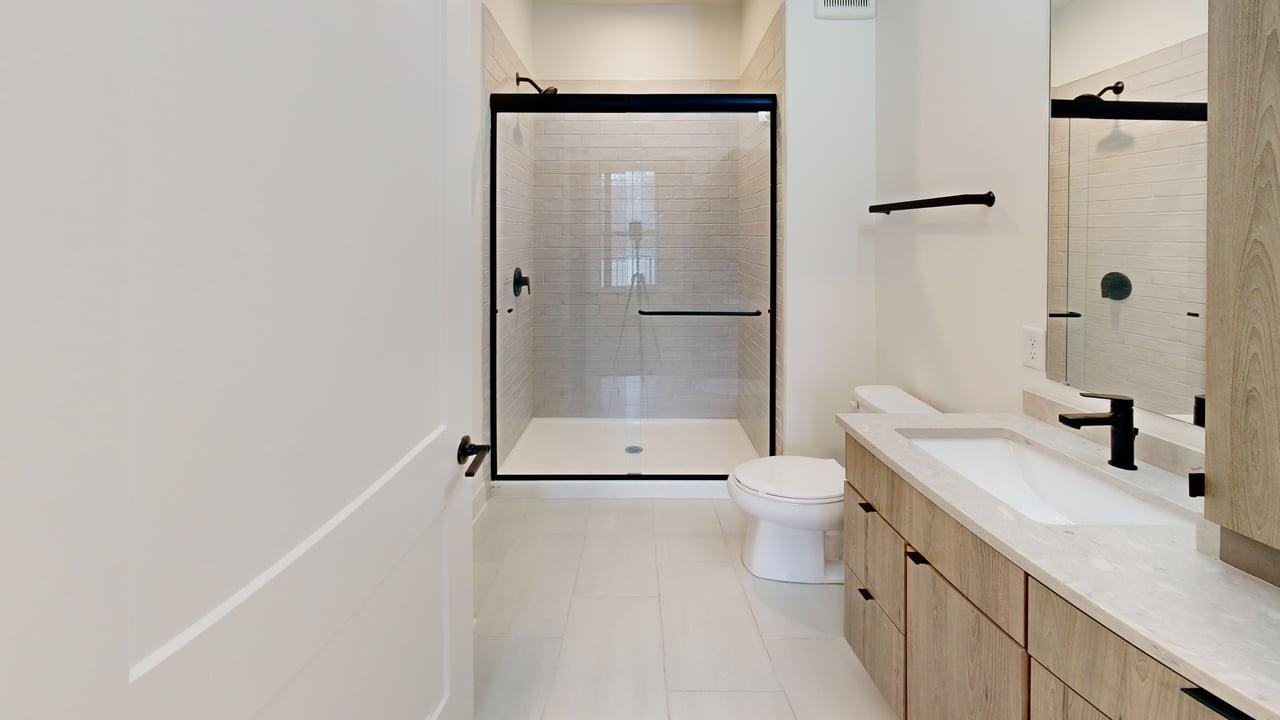 Modern bathroom featuring a sleek glass-enclosed shower, elegant wood cabinetry, and contemporary fixtures.