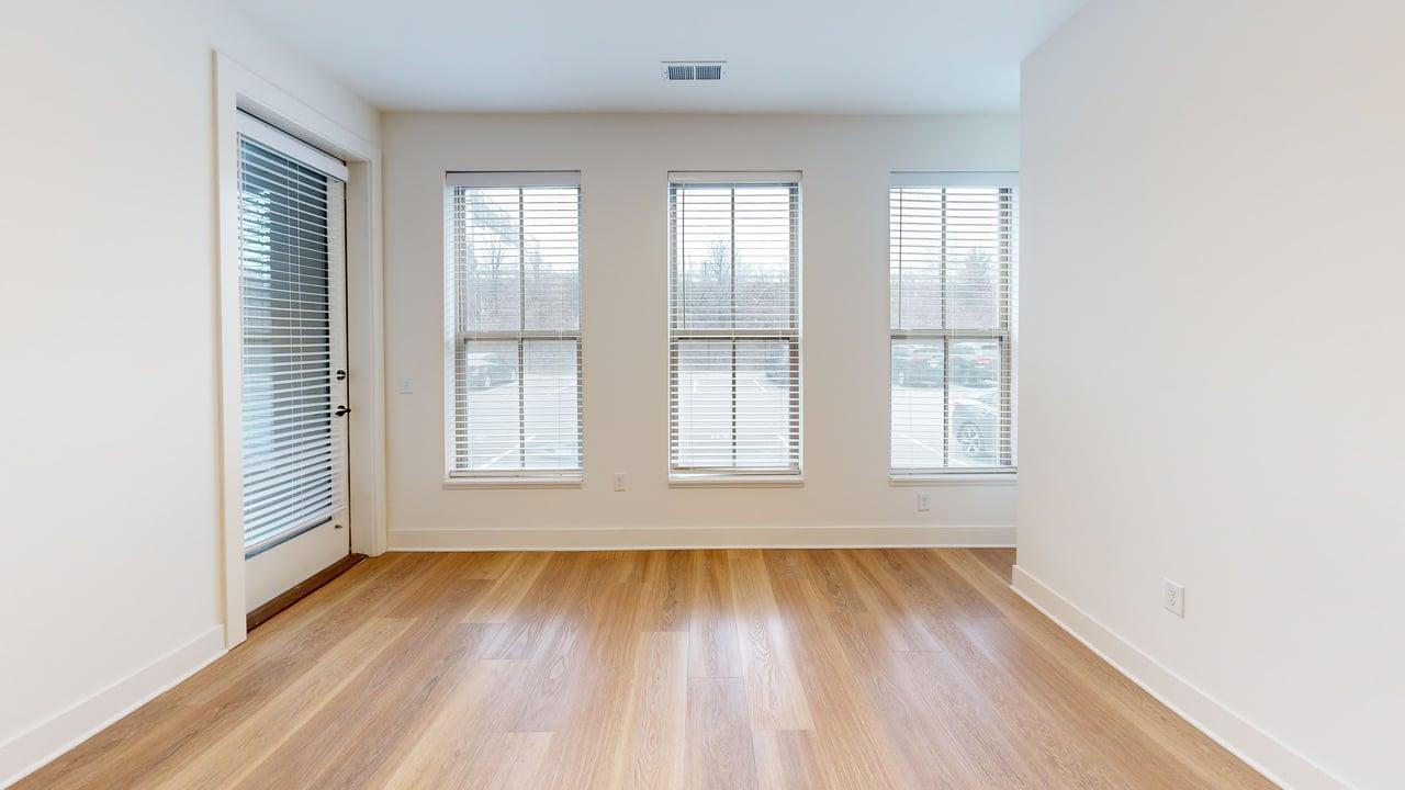 Bright room with hardwood flooring, large windows, and sliding door, perfect for a cozy living space.