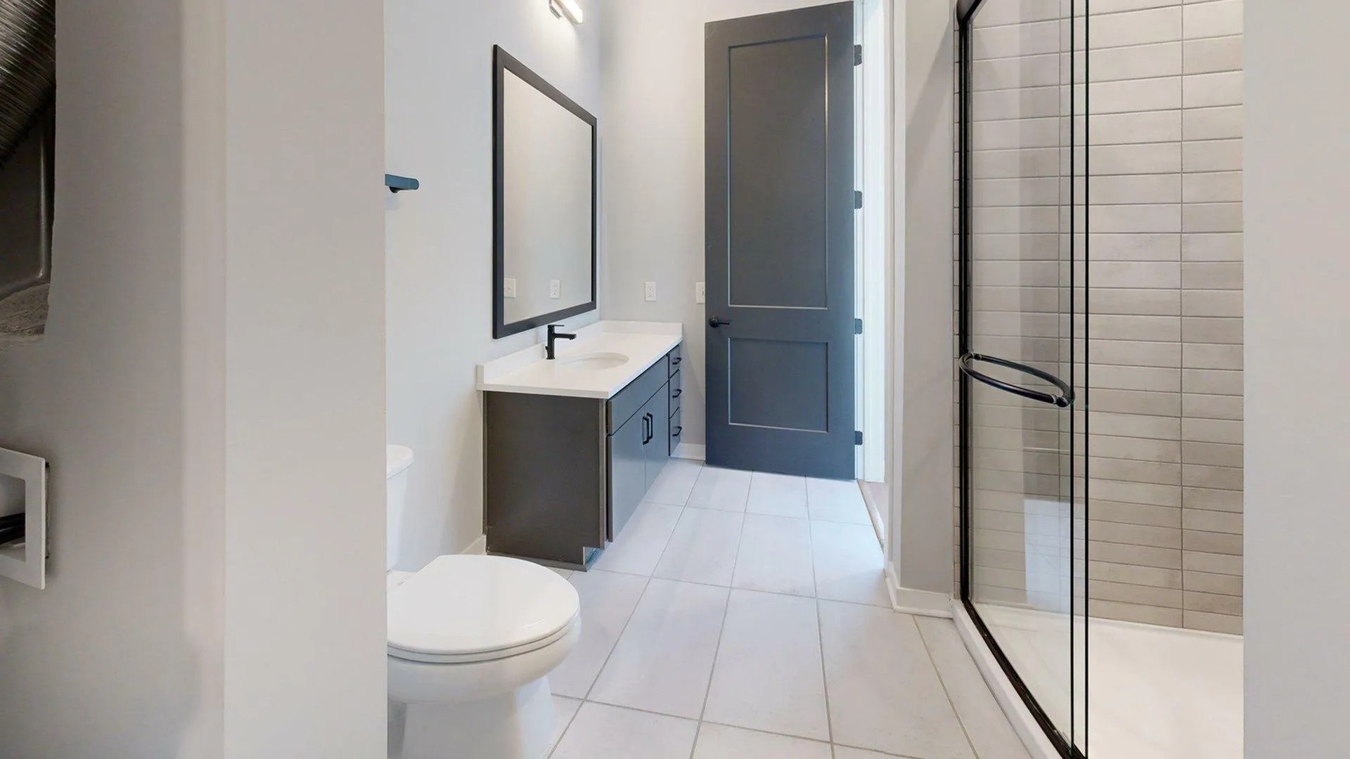 Sleek modern bathroom featuring a glass-enclosed shower, elegant vanity with a large mirror, and sophisticated tile flooring.