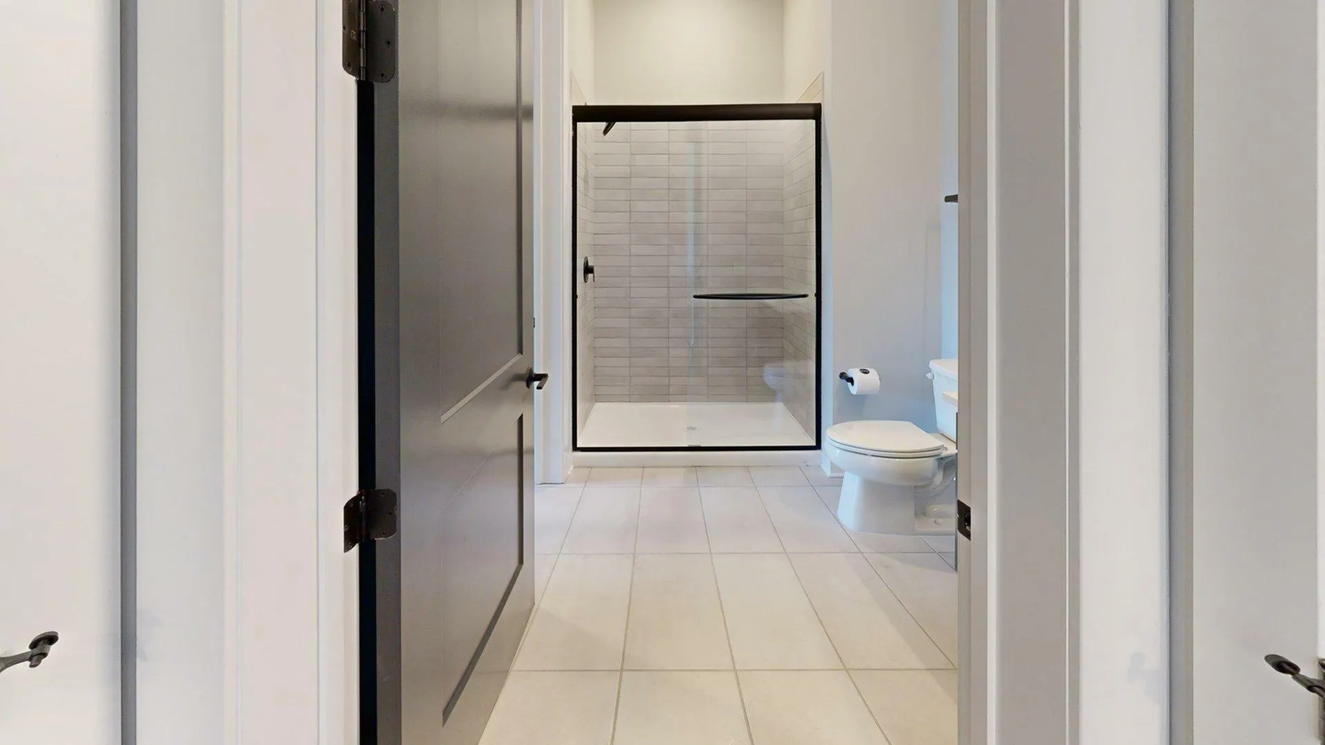 Modern bathroom with sleek glass shower enclosure, elegant tiled floor, and contemporary fixtures.