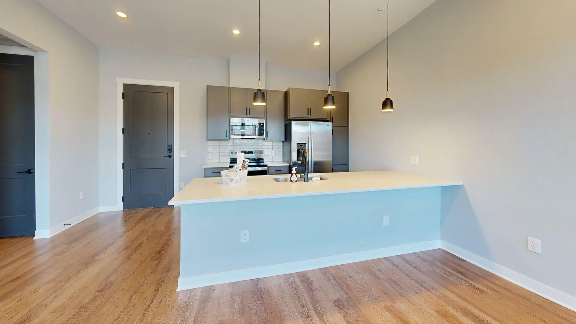 Modern kitchen with sleek gray cabinets, stainless steel appliances, and elegant pendant lighting over a spacious island countertop.