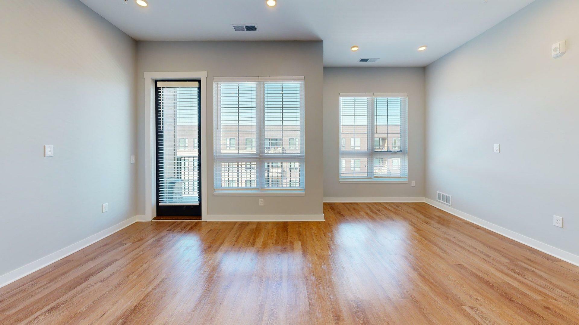 Bright, modern living space with large windows, sleek hardwood floors, and fresh paint, offering a welcoming ambiance.