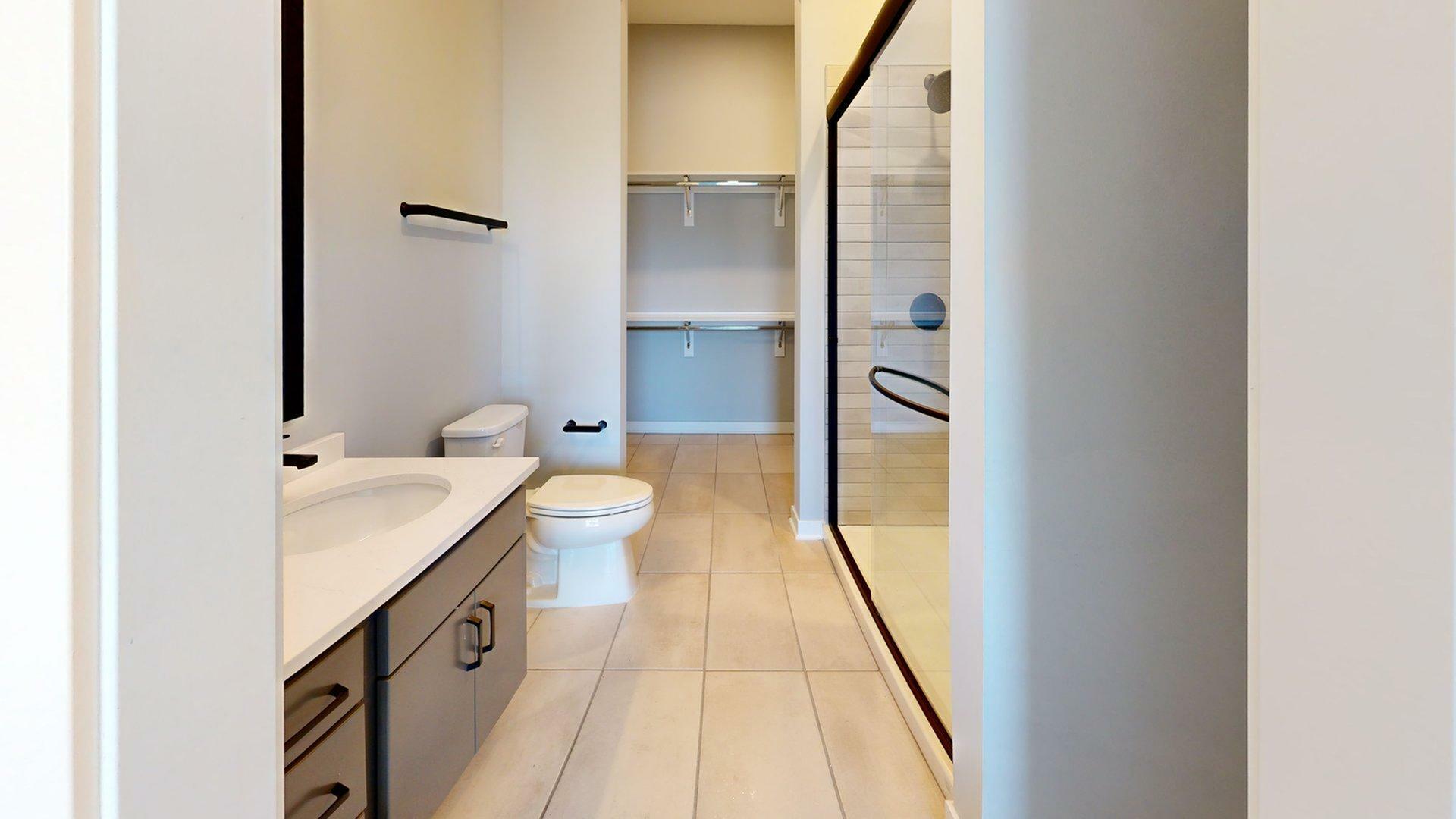 Modern bathroom with sleek vanity, spacious shower, and ample open closet space.