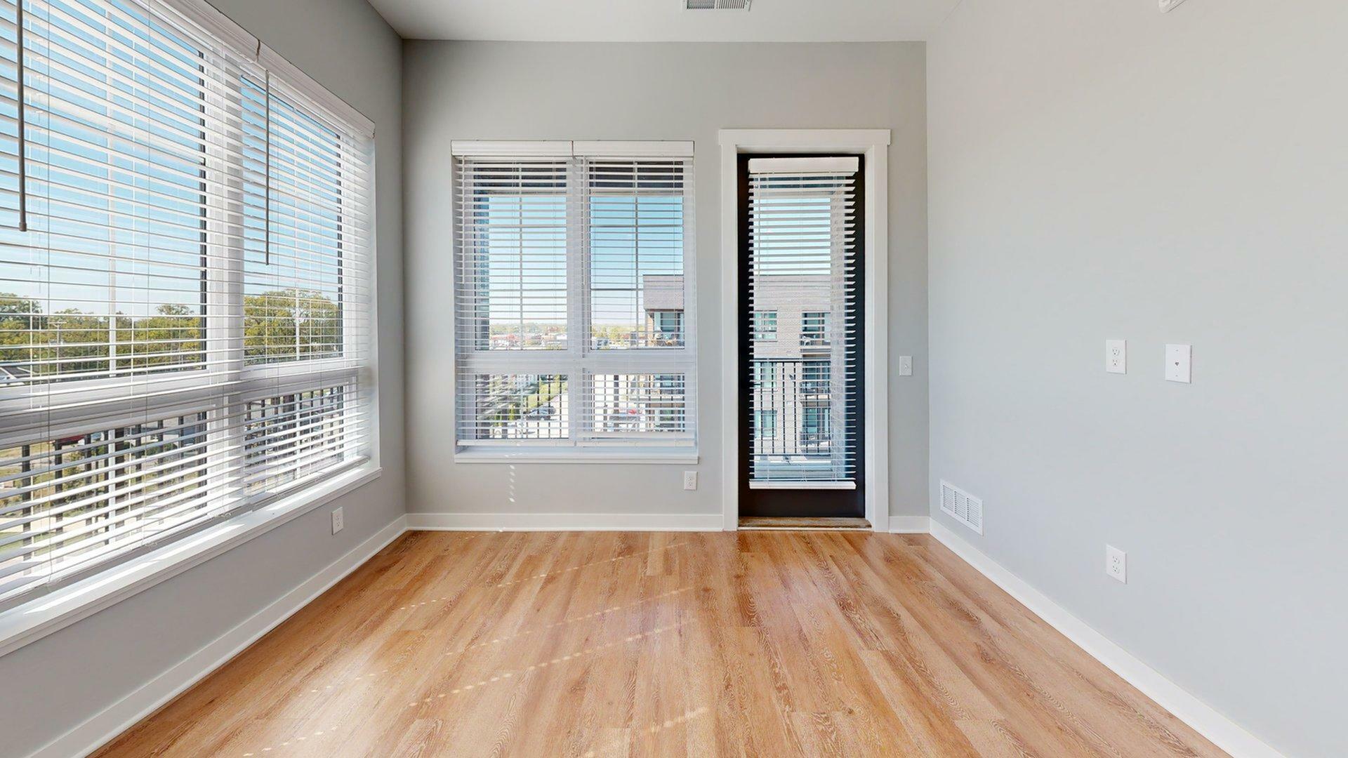 Bright apartment corner with large windows and hardwood floors, offering a stunning view and ample natural light.