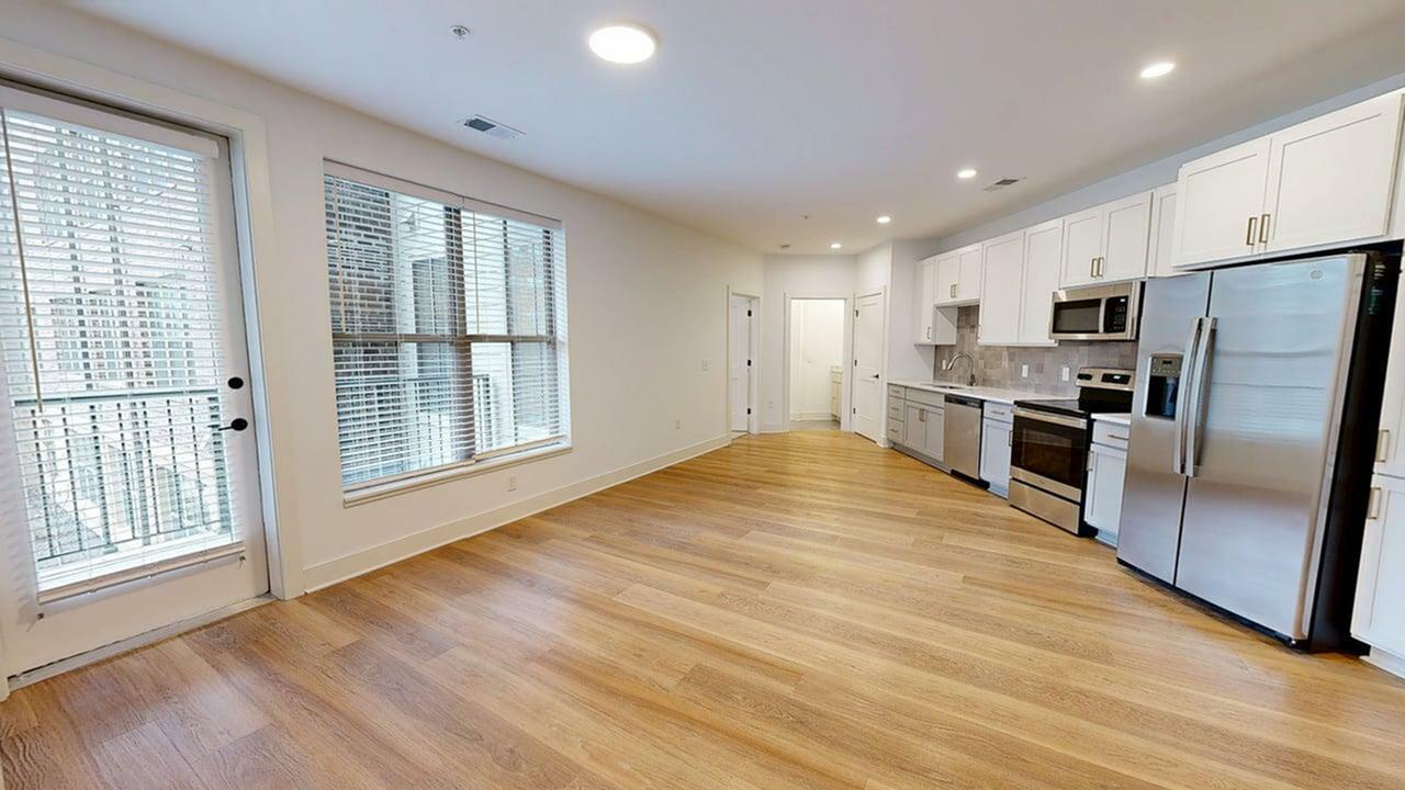 Bright and spacious open-plan kitchen with modern appliances and elegant wooden flooring, enhanced by large windows for natural light.