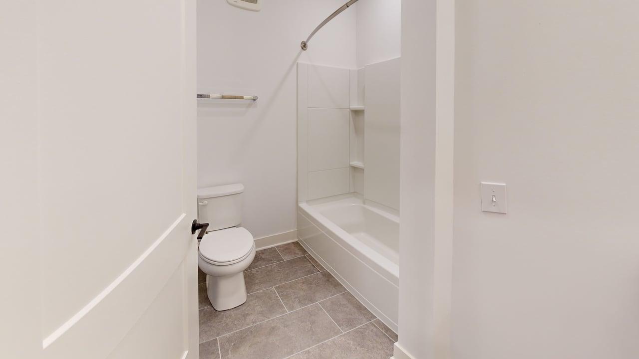 Bright and modern bathroom featuring elegant tile flooring, a sleek bathtub, and a contemporary toilet.