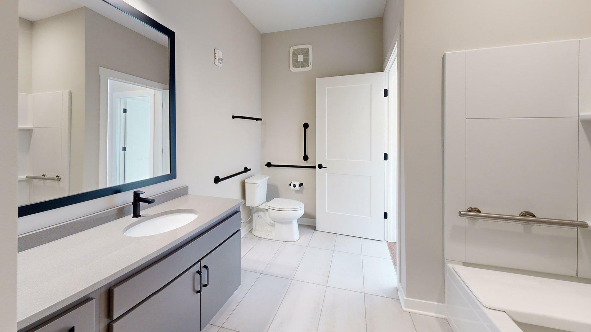 Elegant bathroom featuring a large mirror, modern vanity, and a sophisticated mix of neutral tones, creating a sleek and inviting space.