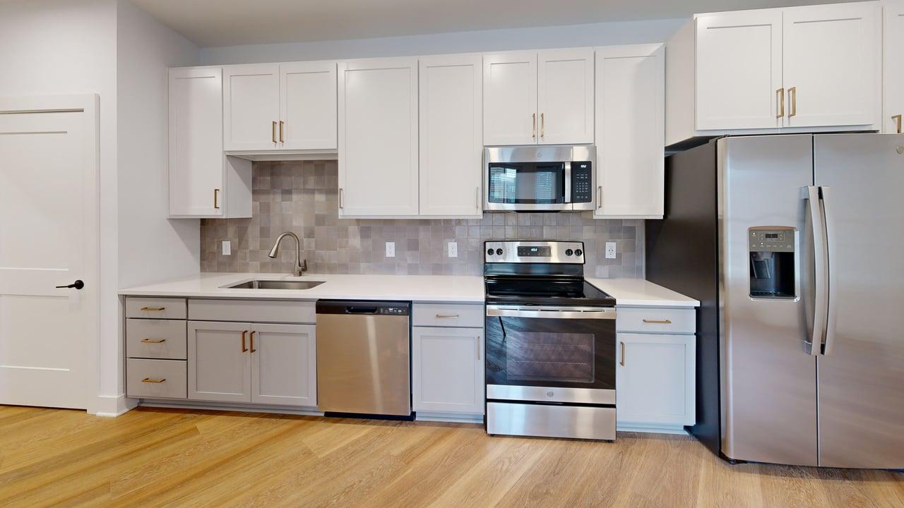Modern kitchen with sleek stainless steel appliances, elegant white cabinetry, and stylish tile backsplash.