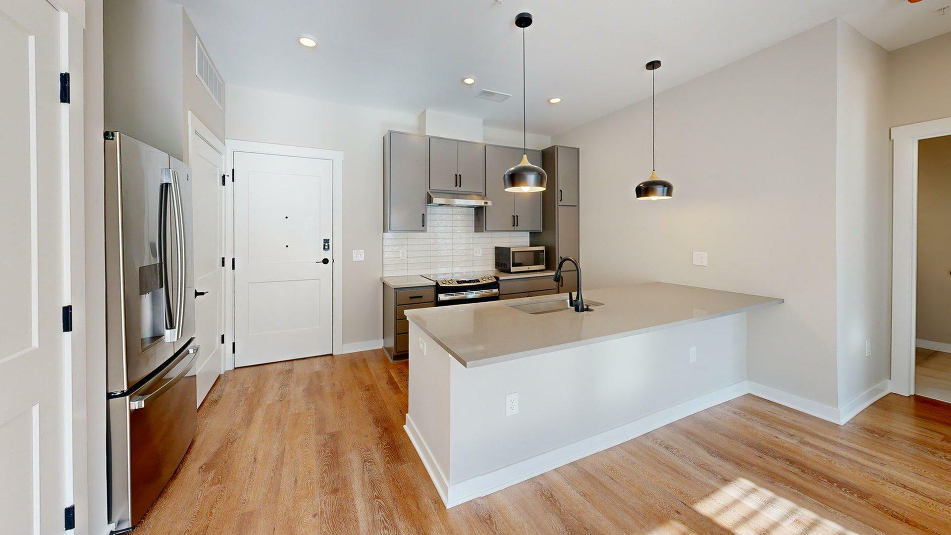 Modern kitchen with sleek gray cabinetry, stainless steel appliances, and elegant pendant lighting over a spacious island.