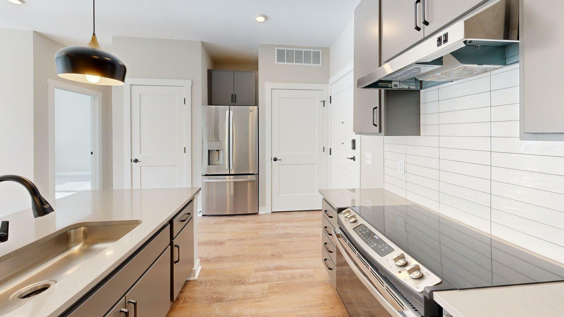 Modern kitchen with sleek stainless steel appliances, elegant countertops, and chic pendant lighting for a contemporary look.