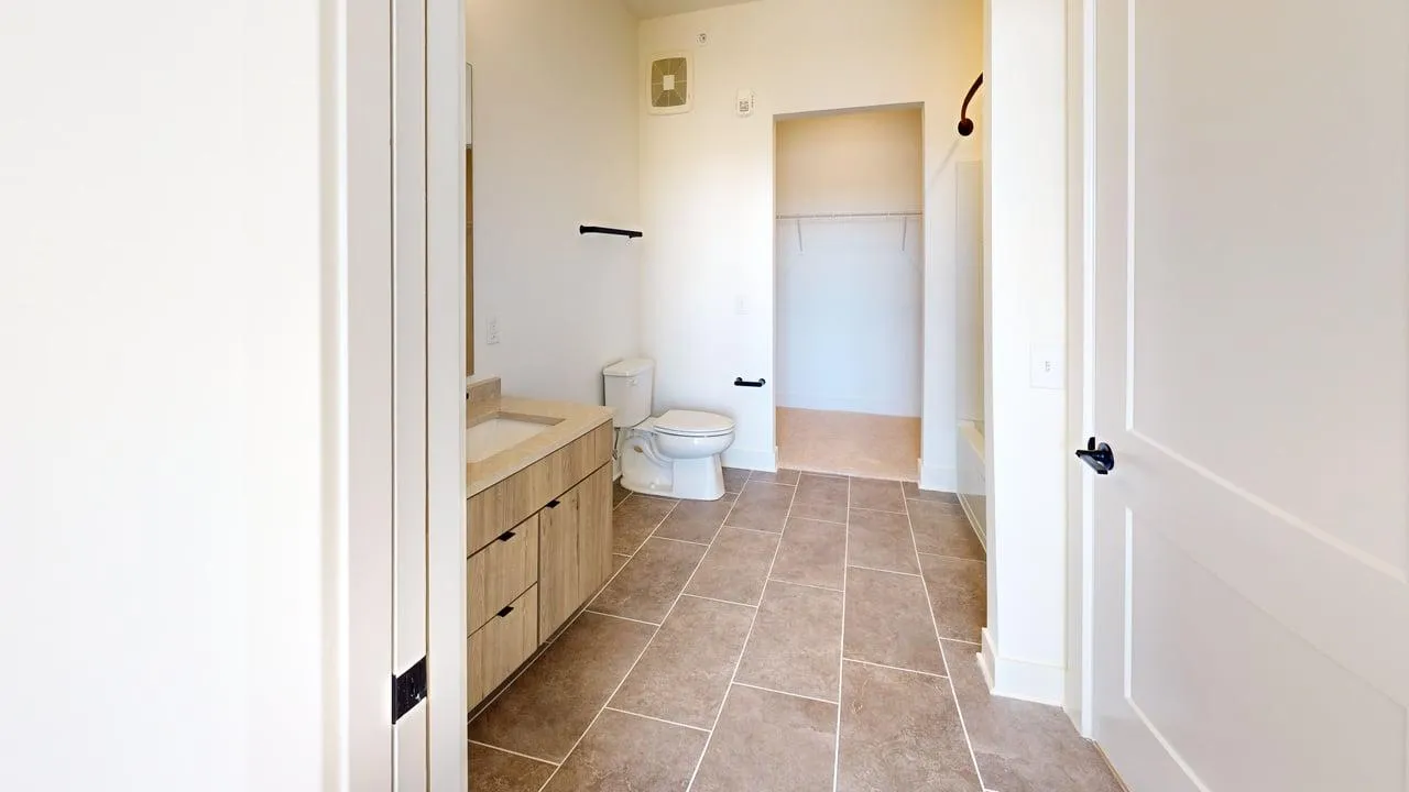 Bright and modern bathroom featuring elegant tiling, spacious vanity, and a walk-in closet.