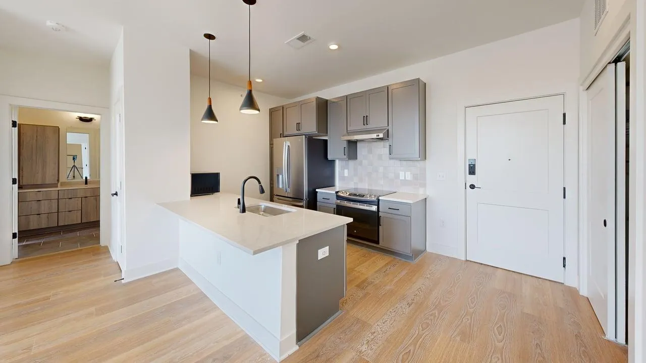 Modern kitchen with sleek cabinetry, stainless steel appliances, and elegant pendant lighting, leading to a stylish bathroom.