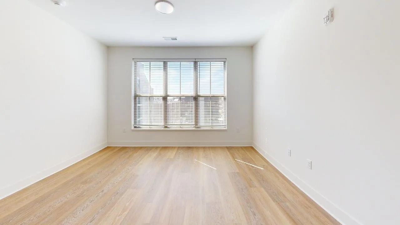 Bright, spacious room with large windows and elegant hardwood flooring.