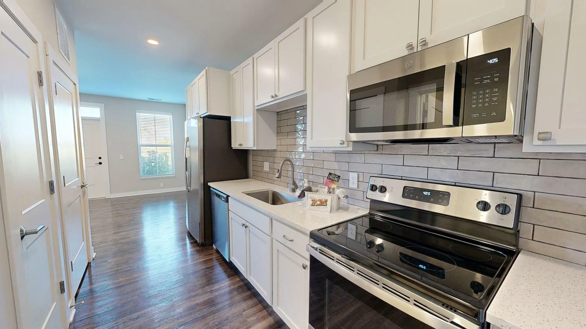 Modern kitchen with sleek stainless steel appliances, white cabinetry, and stylish backsplash, complemented by warm hardwood floors.