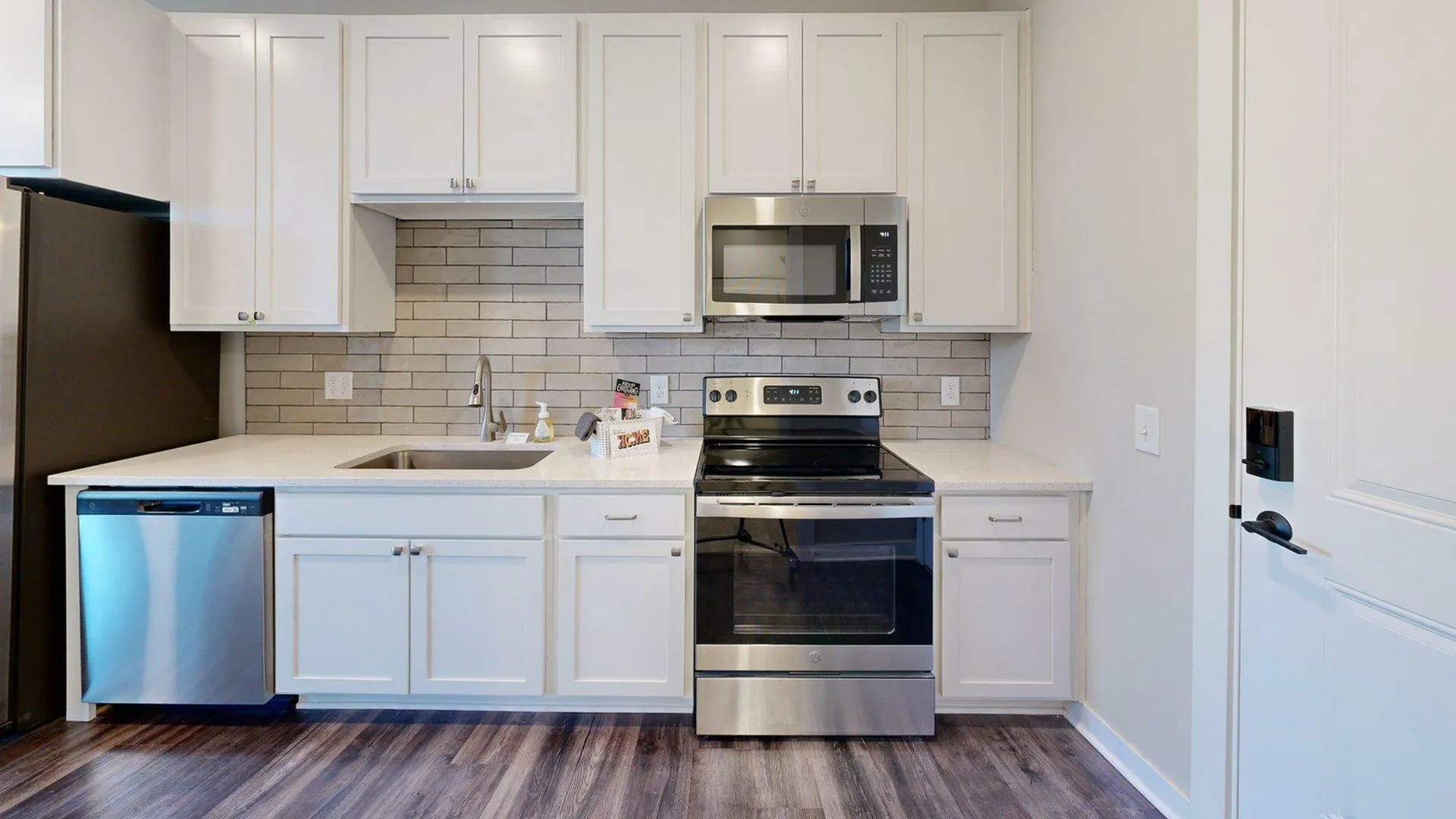 Modern kitchen with sleek white cabinetry, stainless steel appliances, and elegant tile backsplash.