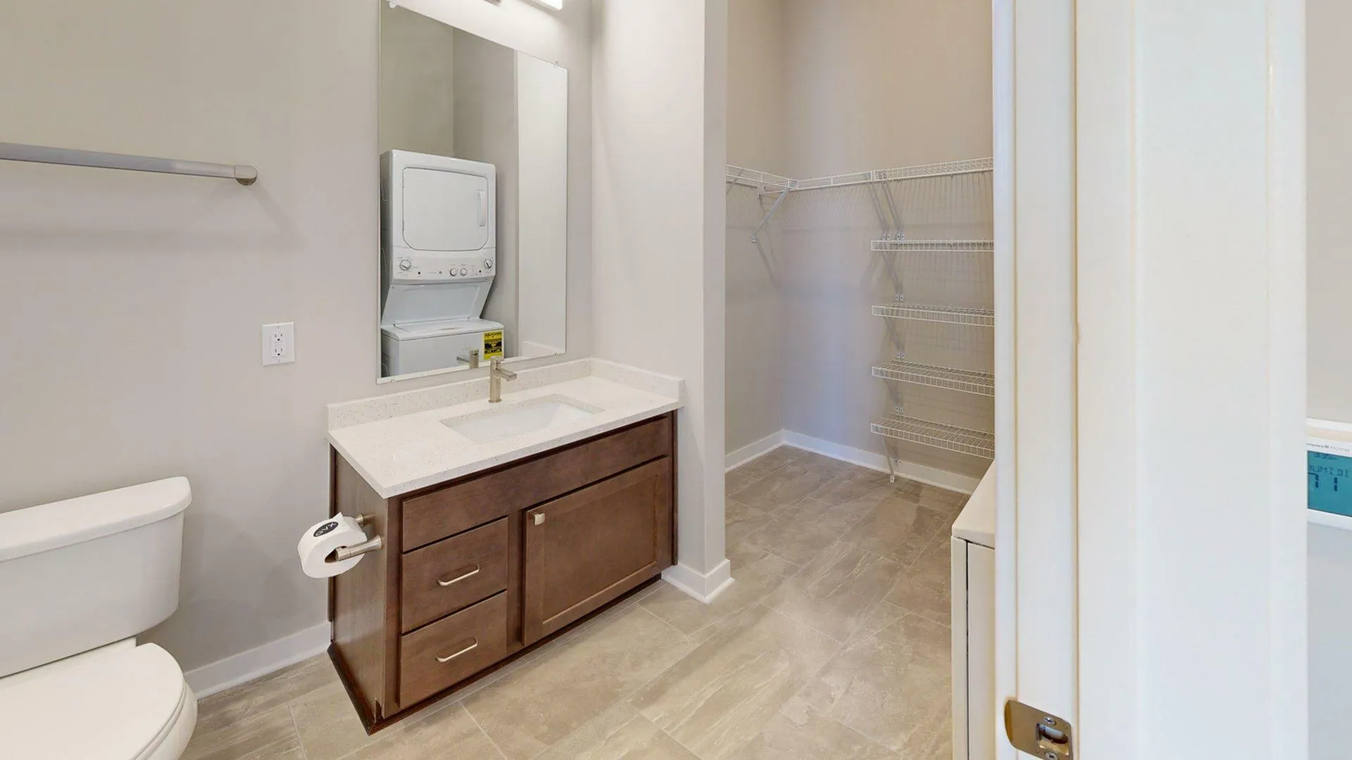 Modern bathroom with sleek vanity, spacious shelving, and convenient in-unit washer and dryer.