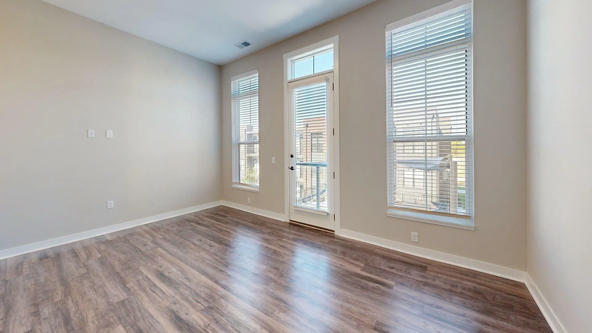Bright, open room with elegant wood flooring and large windows offering natural light and a beautiful view.