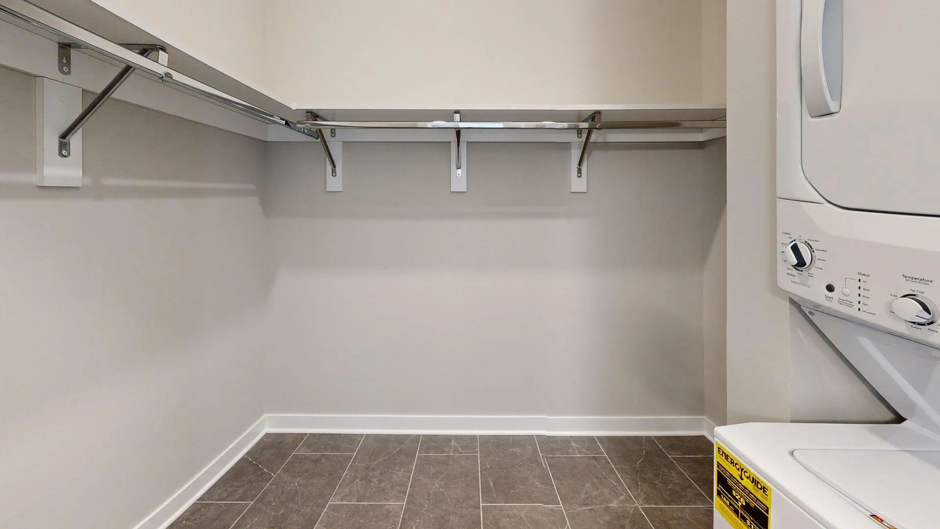 Spacious walk-in closet with built-in shelves and a convenient in-unit washer and dryer.