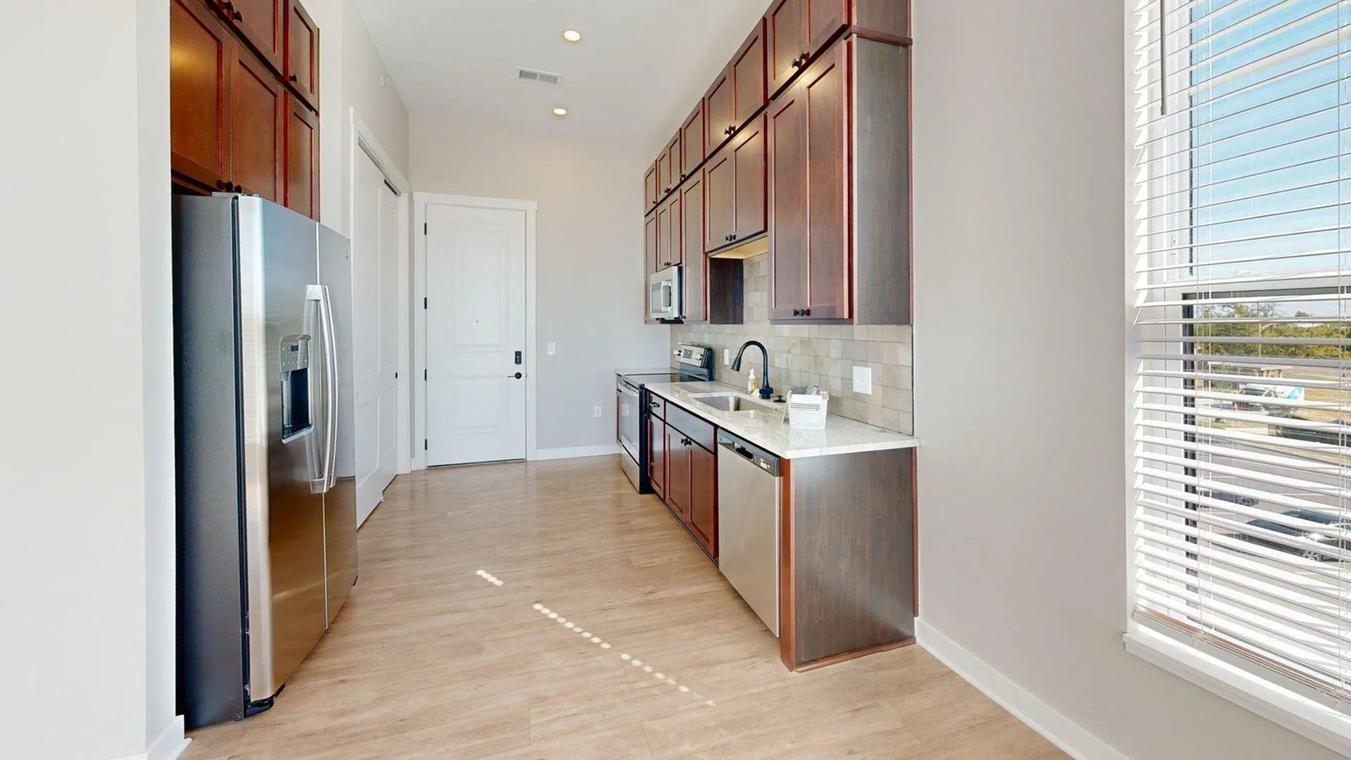 Contemporary kitchen with elegant wooden cabinets, stainless steel appliances, and abundant natural light from large windows.